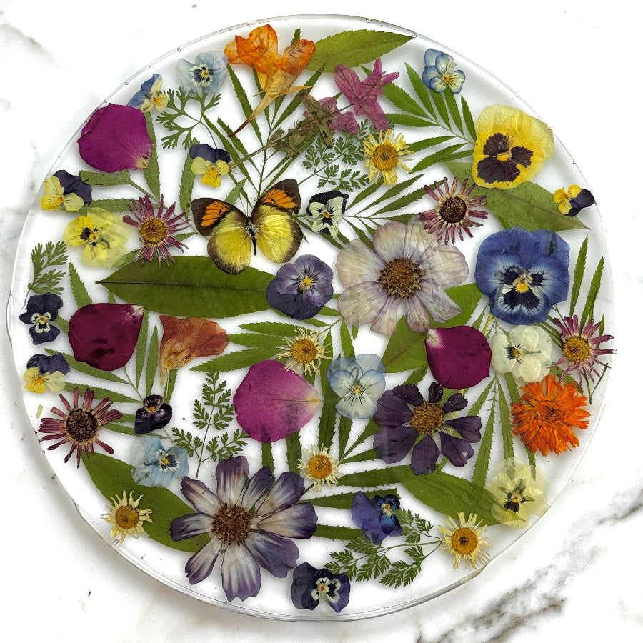 Resin platter with pressed flowers and butterflies on a white background